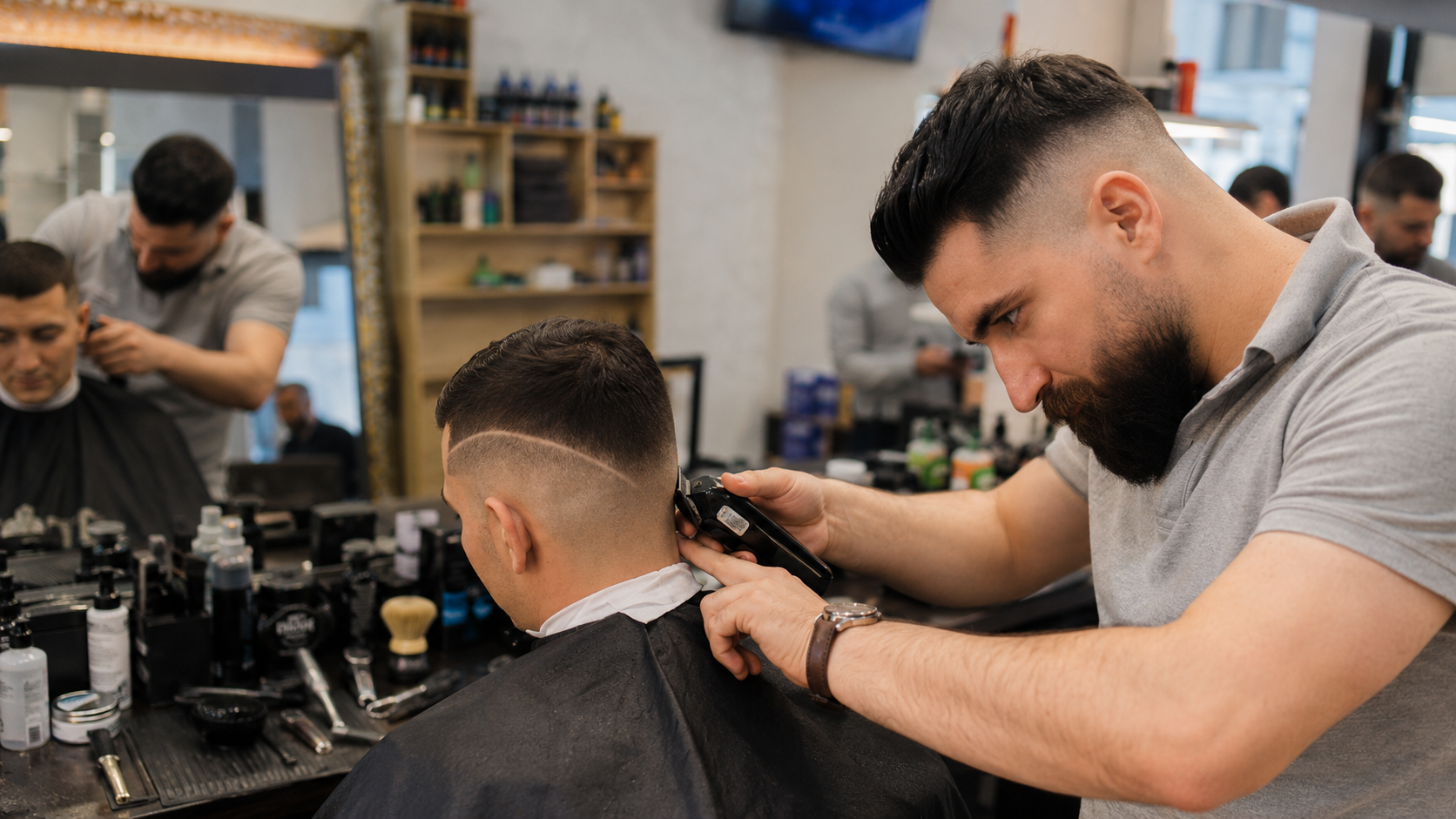 Barbier von Boss Coiffeur beim präzisen Fade-Haarschnitt eines Kunden